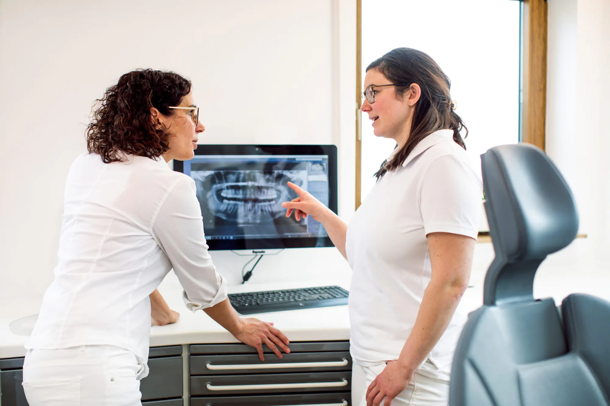 Zahnärztinnen mit digitalem Röntgenbild auf dem Monitor